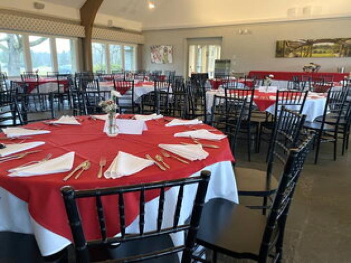 McCormick's Moakley Banquet Room.  The room is setup with round tables, red and white linens, and dishware.